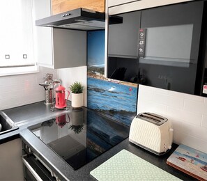 A kitchen with a black countertop, a toaster, a kettle, and a small potted plant. - Two-Bedroom Chalet at Penstowe Park, Near Bude Beaches (Kilkhampton)