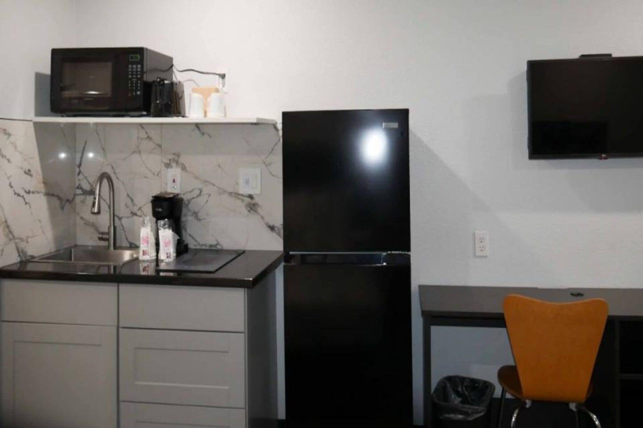 A compact kitchen with a refrigerator, microwave, and sink.