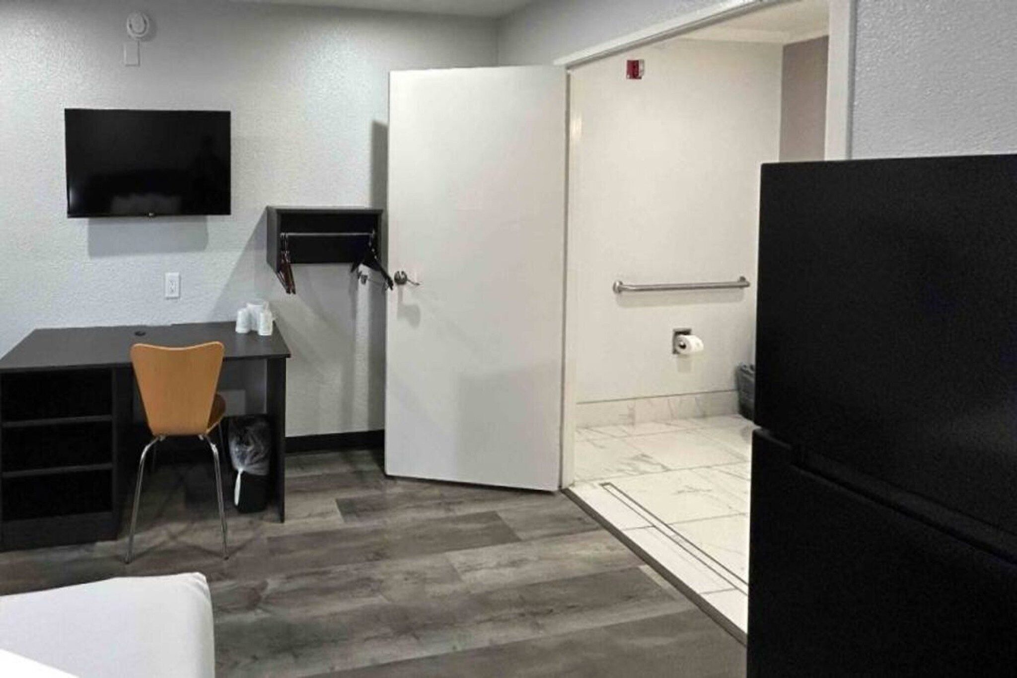 A compact room with a desk, chair, and a black refrigerator.