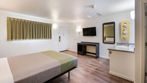 Una habitación de hotel con una cama, un escritorio, un espejo y un televisor.