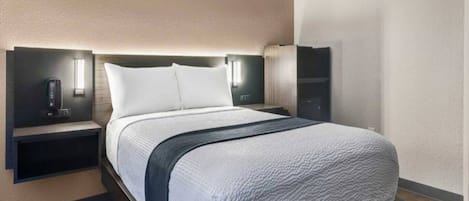 A modern hotel room with a large bed, bedside tables, and wall-mounted lighting.