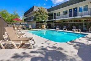 Ein Pool mit Liegestühlen und ein Gebäude mit Balkonen.