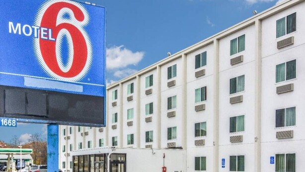 A motel with a large sign, a parking lot, and a building with multiple windows. - 1 Queen Bed | Deluxe (Issaquah)