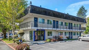 A multi-story motel with a parking lot in front. - 1 Queen Bed | Deluxe (Issaquah)