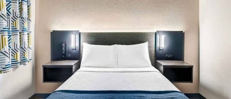 A hotel room with a bed, two bedside tables, a headboard, and a wall-mounted light fixture.