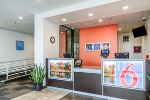 A hotel reception desk with a clock, a digital display, and a sign indicating the hotel name. - 2 Full Beds | Deluxe (Issaquah)