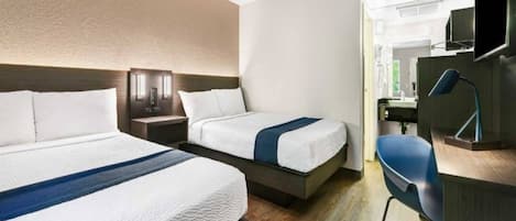 A hotel room with two beds, a desk, a chair, and a bathroom visible through an open door.