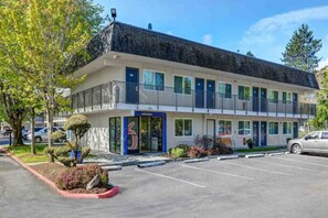 Um motel com vários andares e estacionamento em frente.