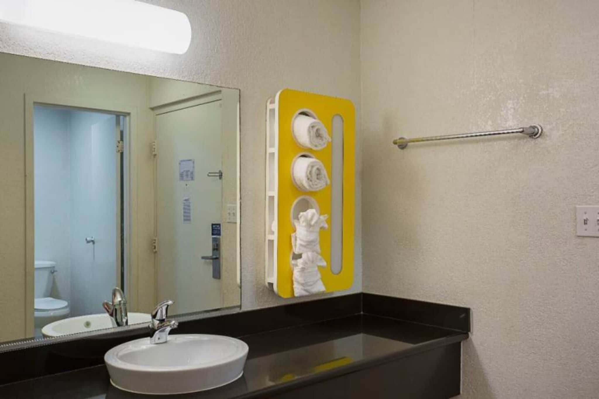 A bathroom with a sink, mirror, and towel rack.