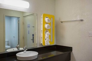 A bathroom with a sink, mirror, and towel rack.