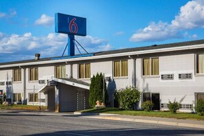 A hotel with a prominent blue sign with the number 6, a covered entrance, and a parking lot in front. - Elegant 1 Queen Bed | Non-Smoking (Wenatchee)