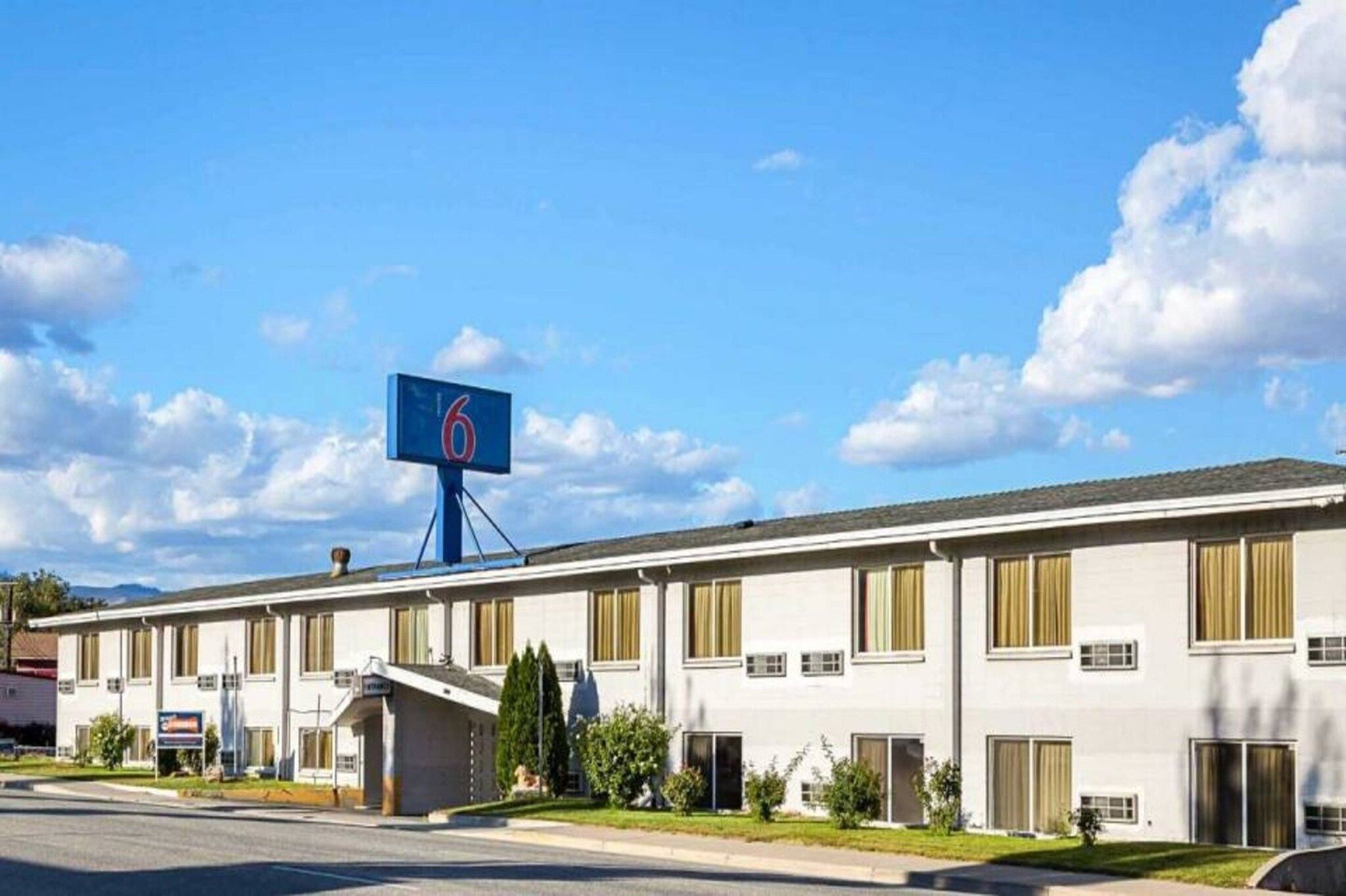 Un motel de dos pisos con un llamativo letrero azul que muestra el número 6.