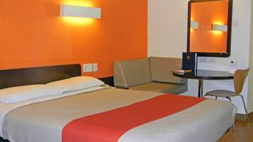 Habitació d'hotel amb llit, escriptori, cadira i un gran mirall.