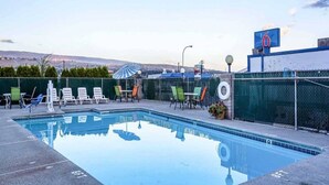 Une piscine avec des chaises longues et un espace salon abrité.