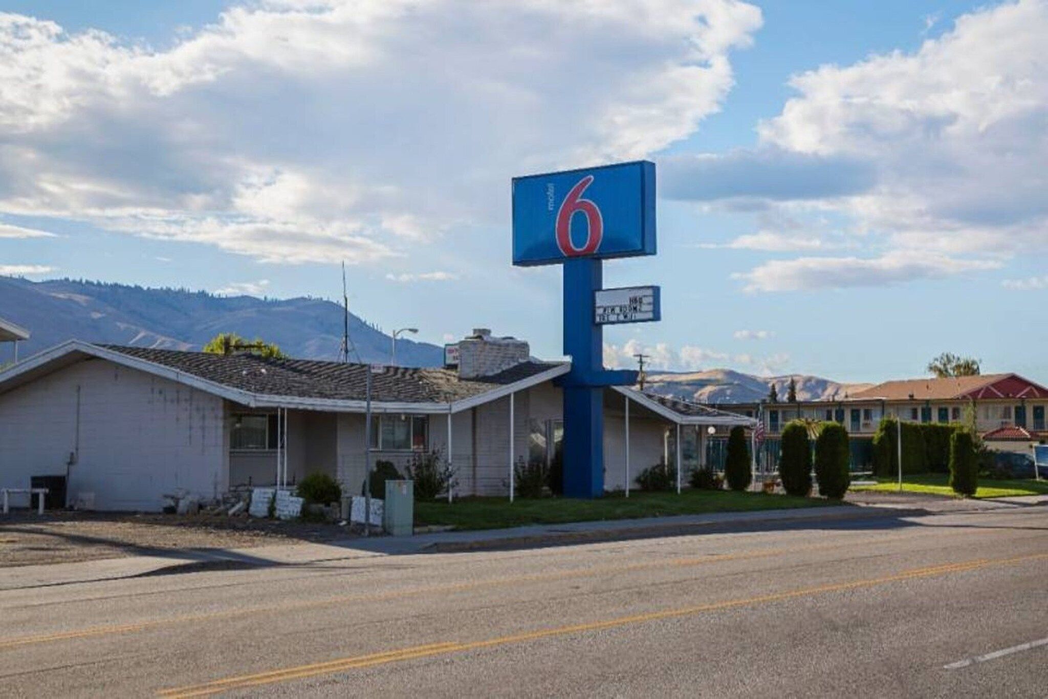 A motel with a prominent '6' sign, a single-story structure, and a parking lot.