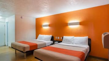 Een hotelkamer met twee bedden, een houten vloer en een wandlamp.