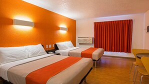 Une chambre d’hôtel avec deux lits, une petite table, une chaise et une fenêtre avec des rideaux.