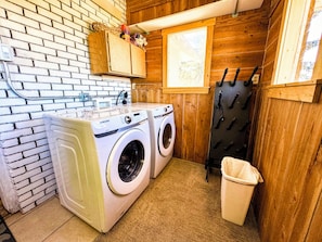 A laundry area with two Samsung washing machines, a sink, a window, and a wooden wall. - 5-Bedroom Craftsman Farmhouse With Teton Views (Tetonia)