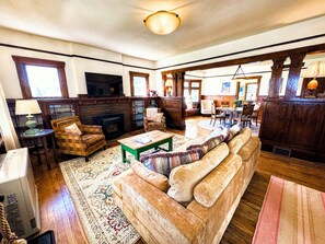 A spacious living room with a fireplace, comfortable seating, and a television. - 5-Bedroom Craftsman Farmhouse With Teton Views (Tetonia)