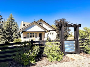 A house with a front porch, a wooden fence, and a pergola with a blue and white striped awning. - 5-Bedroom Craftsman Farmhouse With Teton Views (Tetonia)
