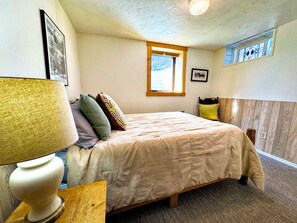 A bedroom with a bed, a nightstand, a lamp, a window, and a wall-mounted picture. - 5-Bedroom Craftsman Farmhouse With Teton Views (Tetonia)
