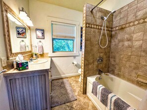 Ein Badezimmer mit Dusche, Waschbecken, Toilette und einem Fenster.