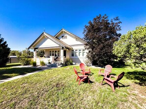 A house with a front porch, a covered entryway, and a lawn with outdoor furniture. - 5-Bedroom Craftsman Farmhouse With Teton Views (Tetonia)