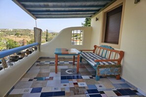 Ein Balkon mit einem gemusterten Boden, einer hölzernen Bank, einem kleinen Tisch und einem Geländer.