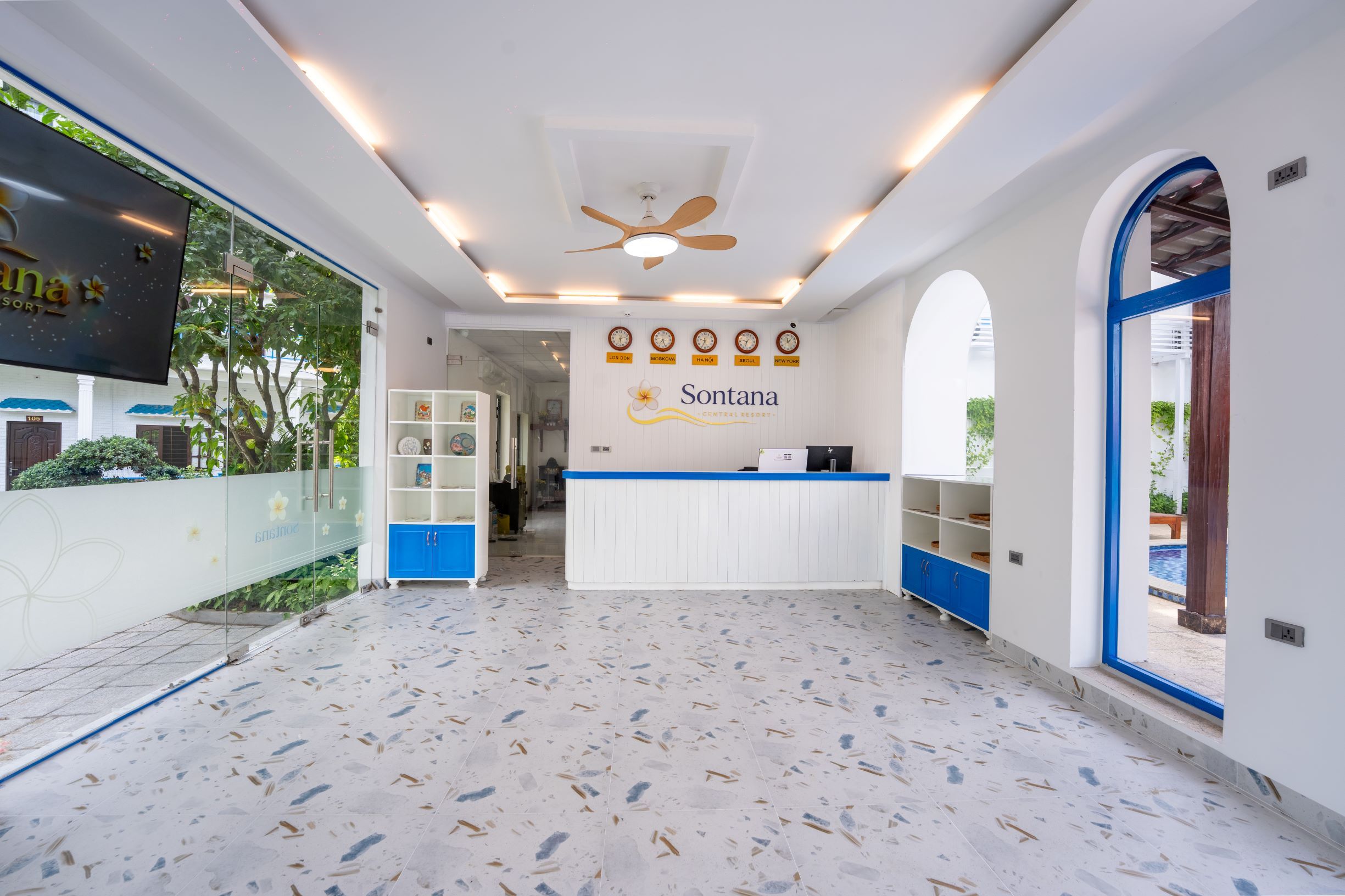 A reception area with a white counter, blue accents, and a ceiling fan.