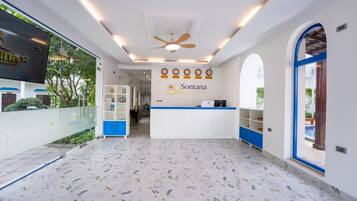 A reception area with a white counter, blue accents, and a ceiling fan.