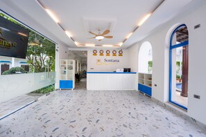 Un área de recepción con mostrador blanco, detalles azules y un ventilador de techo.