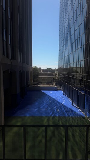 A view of a building's interior with a blue sports court, a metal fence, and a clear sky. - Cozy 1-master bedroom in adorable Downtown, Los Angeles with AC , gym, parking (Los Angeles)