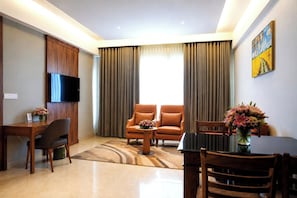 Una sala moderna con televisor de pantalla plana, sillones de cuero, una mesa de comedor con sillas y una mesa de centro.