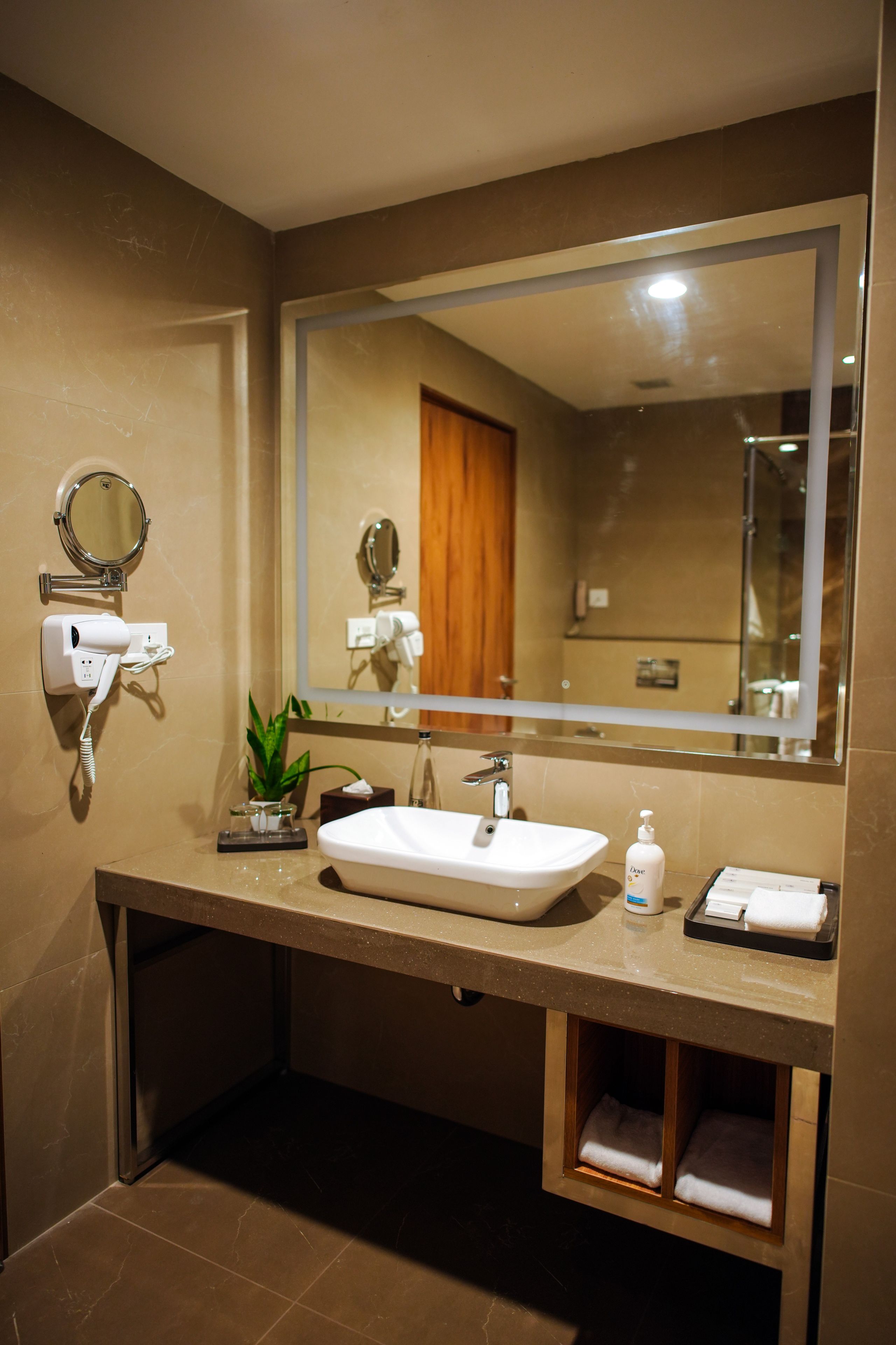 Un baño moderno con un espejo grande, un lavabo, un secador de pelo y un perchero para toallas.