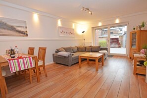 A living room with a sofa, a dining table with chairs, a coffee table, and a cabinet. - Residence-Posthof Apartment 2 (Büsum)