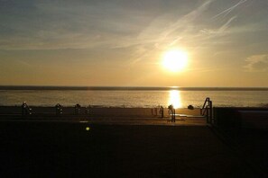 A sunset over a beach with a boardwalk and a railing. - Residence-Posthof Apartment 2 (Büsum)
