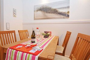 A dining area with a table set for two, featuring a striped tablecloth, a bottle of wine, and a glass. - Residence-Posthof Apartment 2 (Büsum)