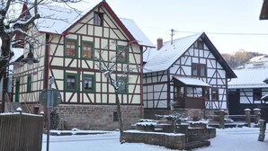Une maison traditionnelle à colombages, avec un toit enneigé et un mur en pierre.