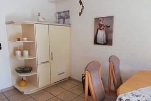 A room with a white cabinet, two chairs, a bed, and a painting on the wall. - Holiday apartment with 1 bedroom (Flörsbachtal-Lohrhaupten)