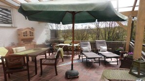 Un espace extérieur aménagé avec une table, des chaises, un canapé et un parasol.