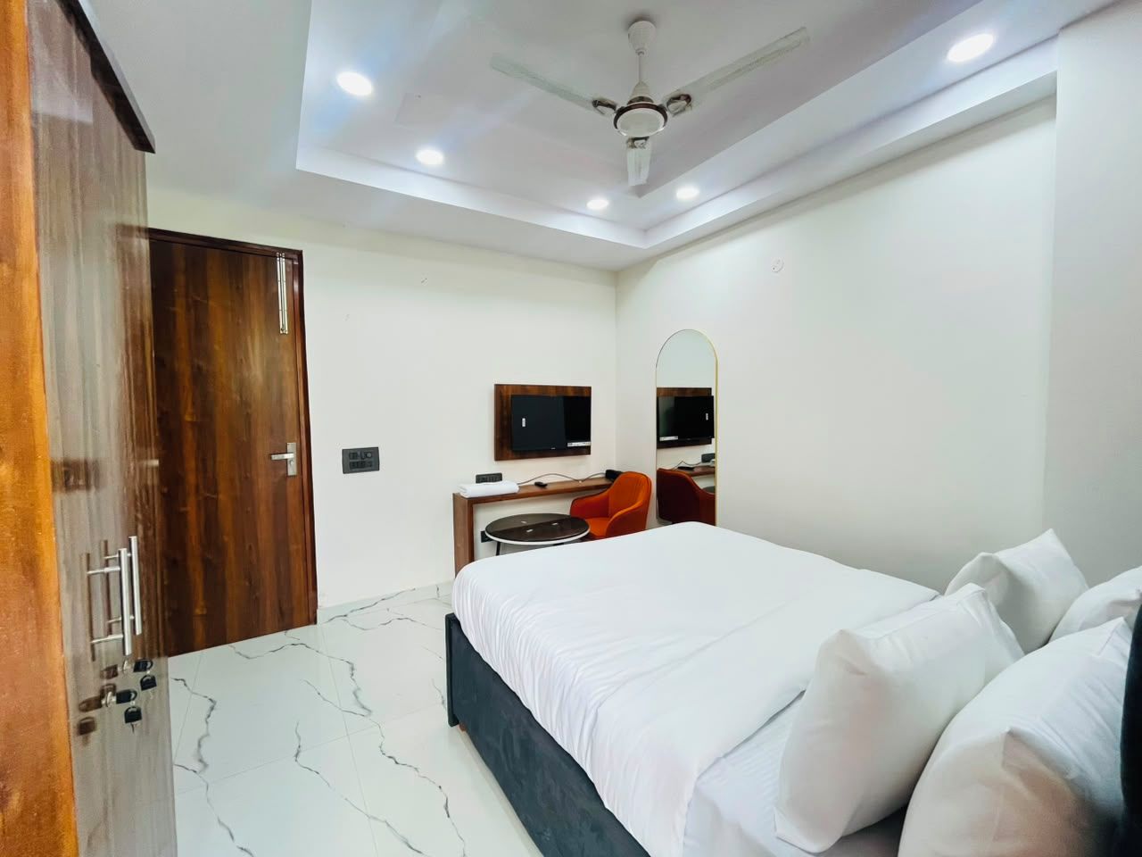 A hotel room with a bed, a desk, a chair, a television, and a wardrobe.