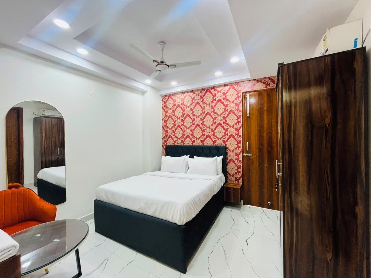 A bedroom with a bed, a wardrobe, a mirror, and a seating area.