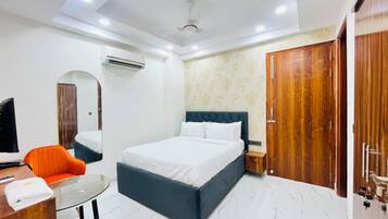 Een hotelkamer met een bed, een bureau met stoel, een airconditioning en een kledingkast.