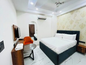 Une chambre d’hôtel équipée d’un lit, d’une petite table, d’une chaise, d’un téléviseur et d’un appareil de climatisation.