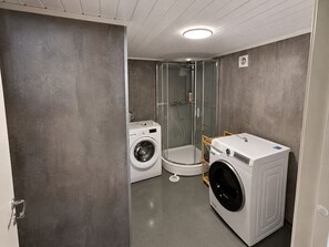 Bany compacte amb rentadora, assecadora i plat de dutxa amb envàs de vidre.