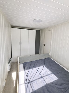 Un dormitorio con cama, armario y radiador.