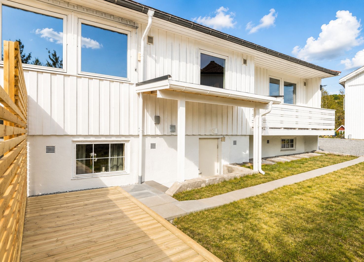 Un bâtiment à deux étages doté d’un porche couvert et d’une terrasse en bois.