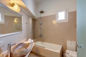 A bathroom with a bathtub, a shower, a toilet, and a mirror. - Faros Village (Syros)