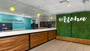 Ett receptionsområde med en bardisk i trä, en blå vägg med texten ”Worldmark by Wyndham” och en grön vägg med ordet ”Aloha”.