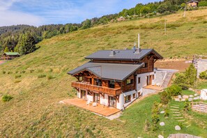 A two-story wooden cabin with a balcony, set on a hillside with a view of a forested area. - Chalet Haute Cime - Les Gets - Les Cornuts (Les Gets)